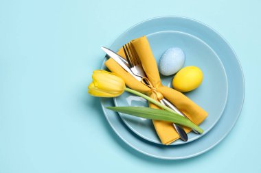 Paskalya kutlaması. Lale çiçekli şenlik masası ve açık mavi arka planda boyanmış yumurtalar, üst manzara. Metin için boşluk