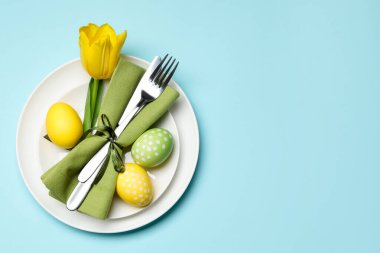 Paskalya kutlaması. Lale çiçekli şenlik masası ve açık mavi arka planda boyanmış yumurtalar, üst manzara. Metin için boşluk