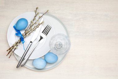 Beyaz ahşap arka planda Paskalya yumurtaları ve söğüt dallarıyla şenlik masası manzarası. Metin için boşluk