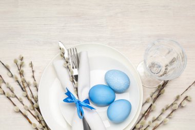 Paskalya yumurtaları ve söğüt dallarıyla bembeyaz ahşap arka planda düzlük masa. Metin için boşluk