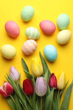 Boyalı Paskalya yumurtaları ve sarı arka planda güzel laleler.