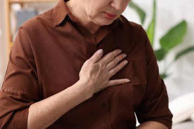 Kalp krizi geçirdi. Üst düzey kadın göğüs ağrısı çekiyor. Kapalı bir yerde, yakın plan.