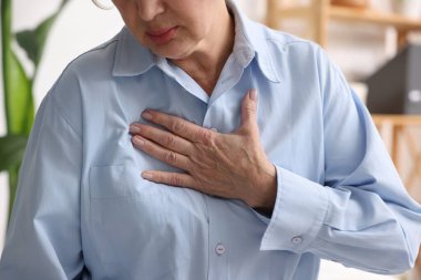 Kalp krizi geçirdi. Üst düzey kadın göğüs ağrısı çekiyor. Kapalı bir yerde, yakın plan.