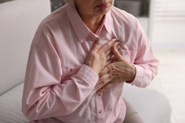 Kalp krizi geçirdi. Üst düzey kadın göğüs ağrısı çekiyor. Kapalı bir yerde, yakın plan.