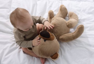 Evde yatağında oyuncak ayıyla küçük şirin bir bebek.