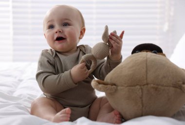 Küçük bebek evde oyuncak tavşanla oynuyor.