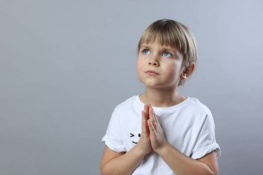 Açık gri arka planda dua eden küçük kız, mesaj için boşluk