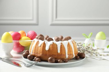 Lezzetli paskalya pastası, çikolatalı şekerler, boyalı yumurtalar ve söğüt dalları kapalı masa üzerinde, yakın plan.