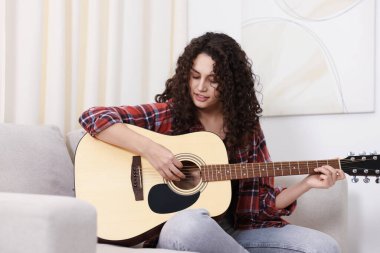 Evdeki kanepede gitar çalan kadın.