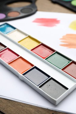 Suluboya resimli paletler ve ahşap masa, yakın plan.