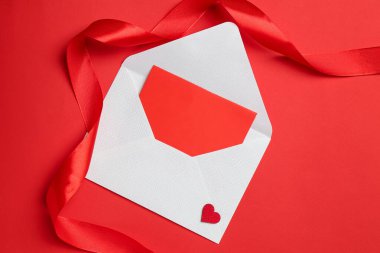 Kırmızı zemin üzerinde aşk mektubu ve kurdele olan zarf, üst görünüm