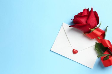 Aşk mektubu ve gül açık mavi arka planda, düz yerde. Metin için boşluk