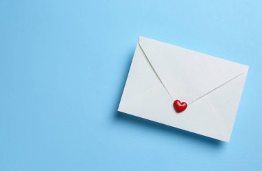 Açık mavi zemin üzerinde kırmızı dekoratif kalp ile zarf, üst manzara. Aşk mektubu