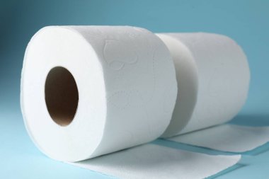 Açık mavi arkaplanda tuvalet kağıdı ruloları, yakın plan