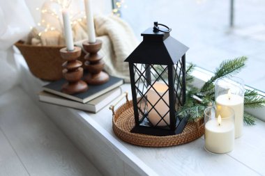 Güzel Noel feneri, yanan mumlar, köknar dalları ve pencere pervazındaki diğer dekorlar, yakın çekim.