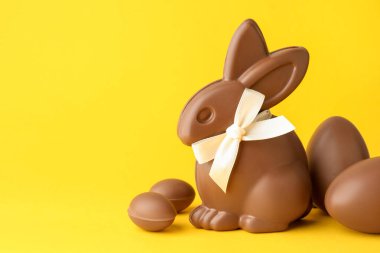 Sarı arka planda çikolatalı Paskalya tavşanı ve yumurta. Metin için boşluk