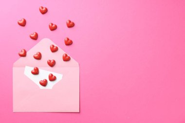 Tebrik kartı ve pembe arka planda dekoratif kalplerle dolu bir zarf. Metin için boşluk