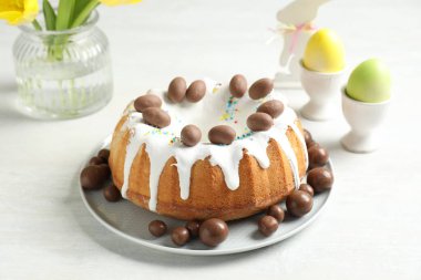 Çikolatalı lezzetli Paskalya pastası, tavşan figürlü ve beyaz masaya boyanmış yumurtalar, yakın plan.