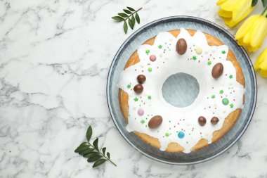 Lezzetli Paskalya pastası, sarı laleler ve beyaz mermer masa üzerinde yeşil yapraklar, düz yatak. Metin için boşluk