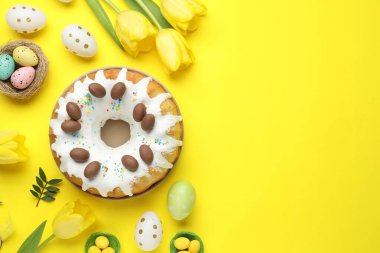 Lezzetli Paskalya pastası, boyanmış yumurtalar, lale çiçekleri ve sarı arka planda yeşil yapraklar. Metin için boşluk