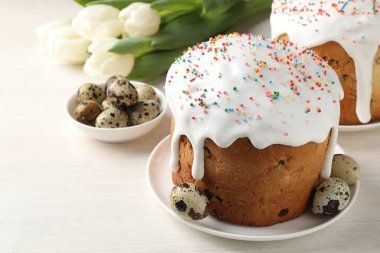 Güzel Paskalya pastaları, yumurtalar ve laleler beyaz masada, yakın plan.