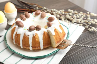 Lezzetli Paskalya pastası. Kapalı masa üzerinde boyalı yumurtalar, sunucu ve söğüt dalları. Yakın plan.
