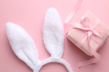 Happy Easter. Bunny ears headband and gift on pink background, flat lay