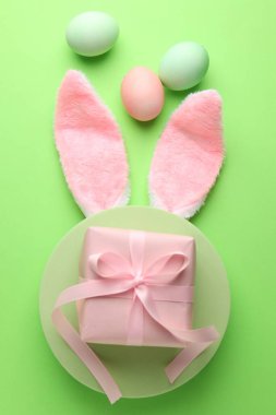 Boyalı Paskalya yumurtaları, tavşan kulaklığı yeşil arka planda hediye, düz uzanma.