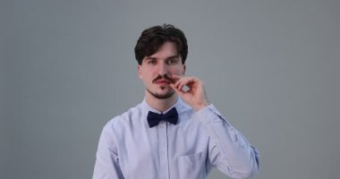 Açık gri arka planda bıyıklı yakışıklı bir adam.