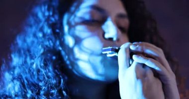 İçerideki renkli ışıklarla mızıka çalan kadın.