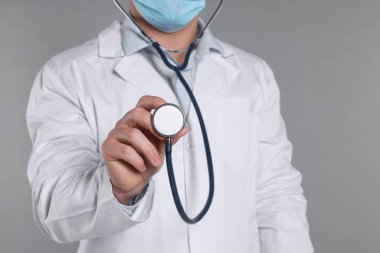 Gri arka planda steteskobu olan doktor, seçici odaklı