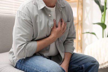 Kalp krizi geçirdi. Kapalı alanda göğüs ağrısı çeken adam, yakın plan.