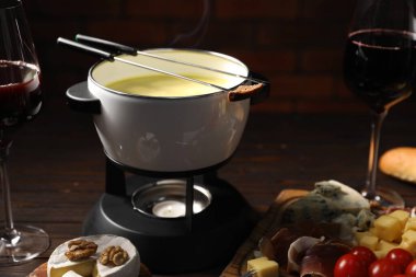 Erimiş peynir, şarap ve atıştırmalıklarla fondü tenceresi (caquelon), yakın plan.