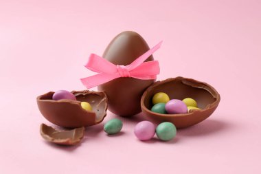 Çikolata yumurtaları ve pembe arka planda renkli şekerler, yakın plan. Mutlu Paskalyalar
