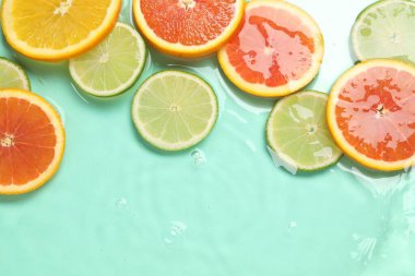 Turkuaz arka planda sudaki turunçgil meyveleri, düzlük. Metin için boşluk