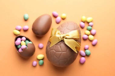Soluk turuncu arka planda çikolatalı Paskalya yumurtası ve şekeri.