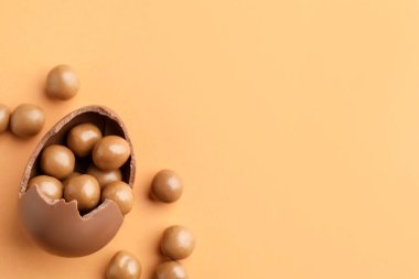 Soluk turuncu arka planda şekerli çikolatalı Paskalya yumurtası. Metin için boşluk