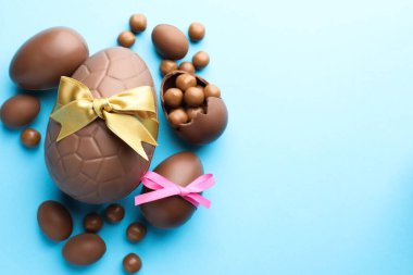 Çikolatalı Paskalya yumurtaları, şekerli ve fiyonklu açık mavi arka plan, düz. Metin için boşluk