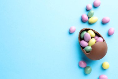 Paskalya kutlaması. Açık mavi arka planda şekerli kırık çikolata yumurtası, düz. Metin için boşluk