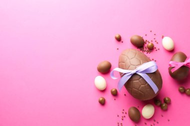 Pembe arka planda şekerli, çikolatalı Paskalya yumurtaları. Metin için boşluk