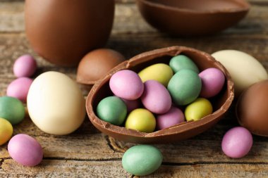 Ahşap masada renkli şekerlemeli lezzetli çikolata yumurtaları, yakın plan. Mutlu Paskalyalar