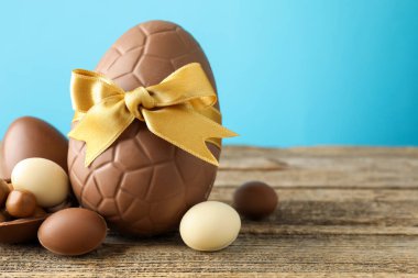 Mutlu Paskalyalar. Ahşap masa üzerinde çikolatalı yumurtalar açık mavi arka planda, yakın plan. Metin için boşluk