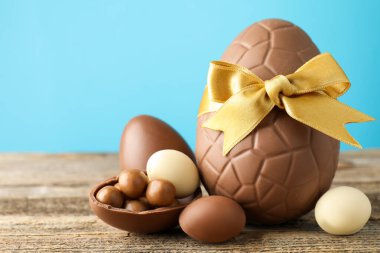 Mutlu Paskalyalar. Ahşap masa üzerinde çikolatalı yumurtalar açık mavi arka planda, yakın plan. Metin için boşluk