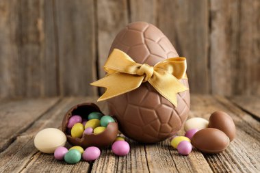 Ahşap masada renkli şekerlemeli lezzetli çikolata yumurtaları, yakın plan. Mutlu Paskalyalar