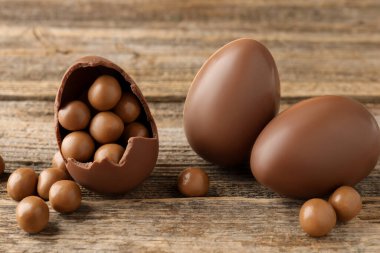 Ahşap masada şekerli çikolatalı yumurtalar, yakın plan. Mutlu Paskalyalar