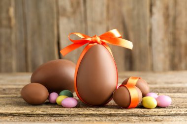 Ahşap masada renkli şekerlemeli lezzetli çikolata yumurtaları, yakın plan. Mutlu Paskalyalar
