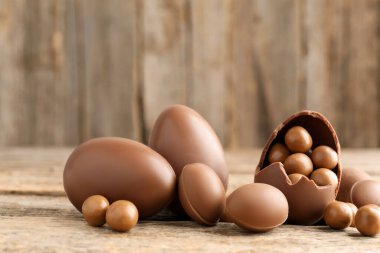 Ahşap masada şekerli çikolatalı yumurtalar, yakın plan. Mutlu Paskalyalar