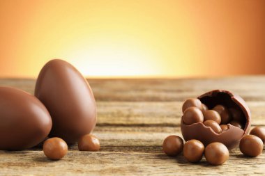 Ahşap masadaki çikolatalı yumurtalar, renkli arka plana karşı, yakın plan. Mutlu Paskalyalar