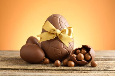 Ahşap masadaki çikolatalı yumurtalar, renkli arka plana karşı, yakın plan. Mutlu Paskalyalar