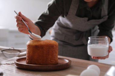 Geleneksel Paskalya pastasını mutfakta jöleli dekore eden genç bir kadın.